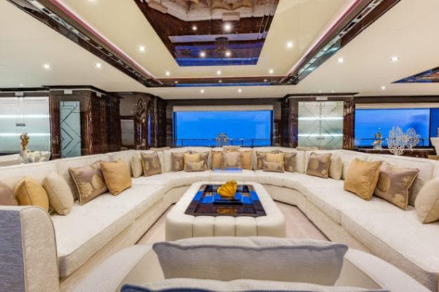 On the main deck, the saloon is dominated by a huge U-shaped couch, with large windows either side
