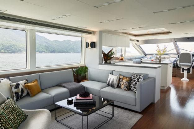 Lit by big windows, the saloon features a lounge and, forward, a large L-shaped kitchen with an island counter, a corner dining table and a single-seat helm station