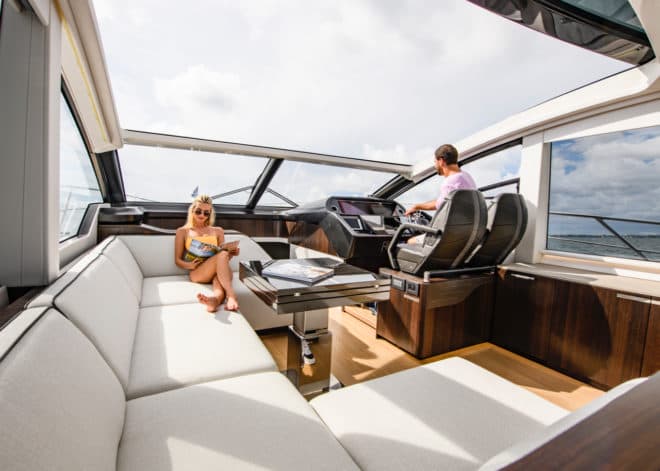 The saloon has white sofas, a black foldout table and a helm with leather bucket seats