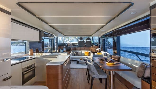 The main-deck interior features a dining table opposite the galley and a comfortable lounge, with floors in bleached oak and panelling in elm and Canaletto walnut